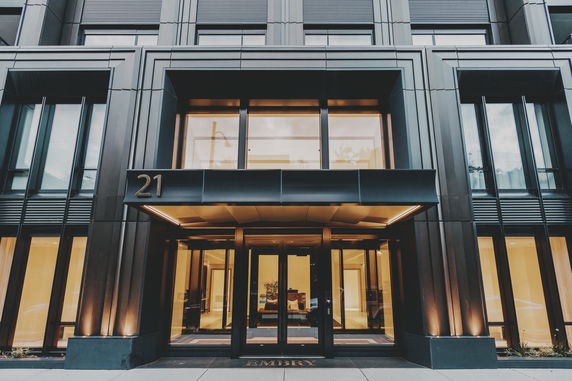 Front view of a modern building entrance with glass doors and metal facade.
