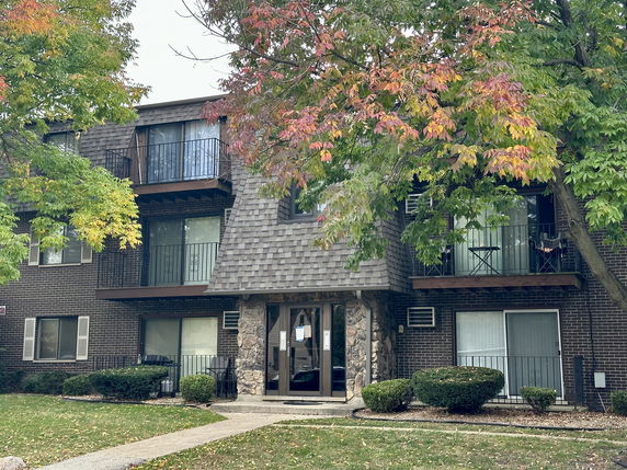 Front view of a three-story apartment building with a brick facade and small balconies.