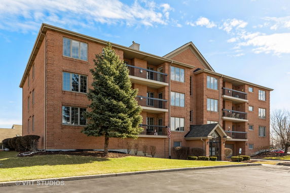 Front view of a multi-story brick apartment building with balconies.