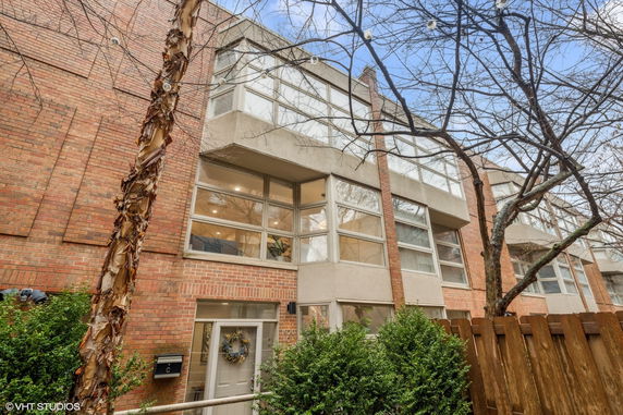 Front view of a multi-story brick house with large windows.