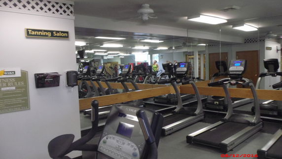Indoor gym area with multiple treadmills and mirrored walls.