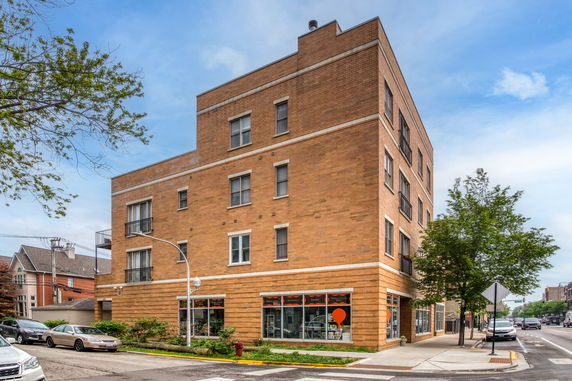 Corner view of a multi-story brick building on a street corner.