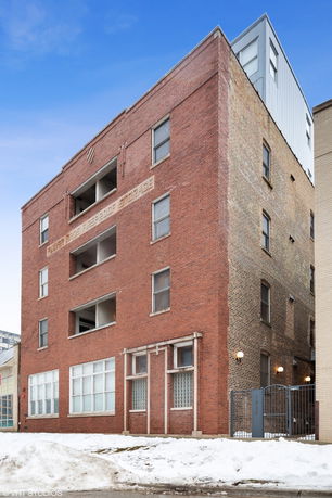 Front view of a multi-story brick building with windows and a gated entrance.