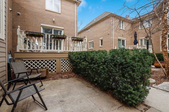 View of patio area and neighboring houses with brick exteriors and small yards.