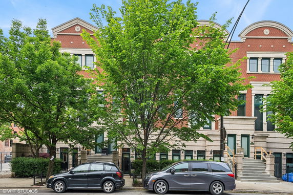 Front view of a brick multi-story building with arched tops and large windows.