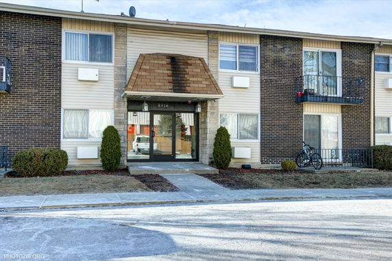 Front view of a two-story apartment building with a central entrance and balconies.