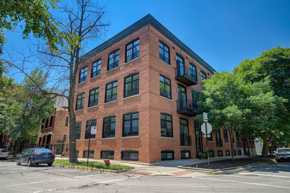 Front view of a multi-story brick building on a street corner.
