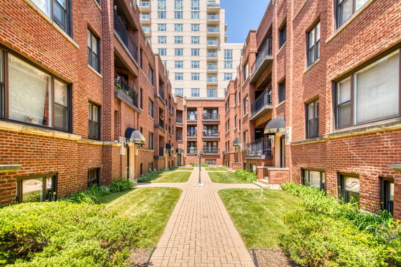 Front view of a multi-story brick apartment building with balconies.