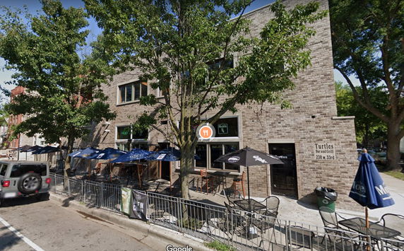 Front view of a brick building with outdoor seating.