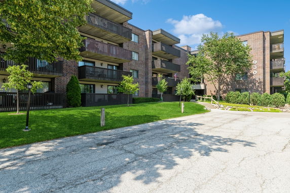 Front view of a multi-story brick apartment building with balconies.