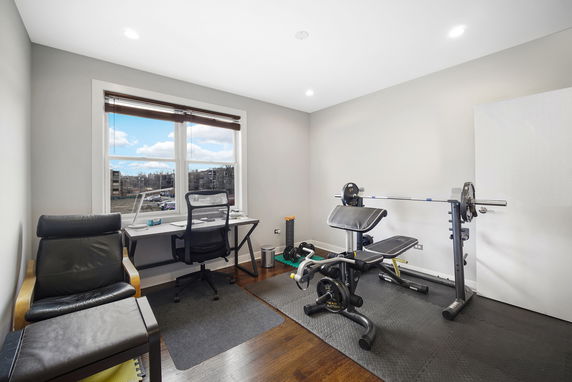Room with exercise equipment and a workspace.
