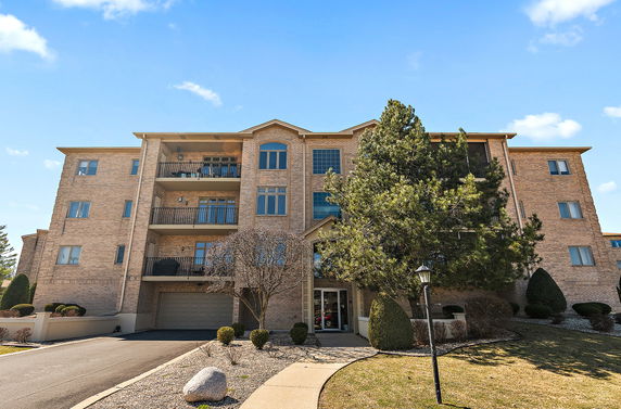 Front view of a multi-story building with balconies and a garage entrance.