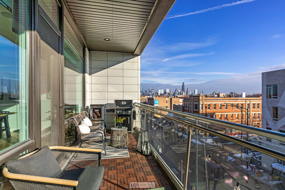 A balcony view of an urban skyline, capturing city buildings under a clear blue sky.