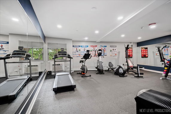 Indoor gym area with exercise machines and mirrors.