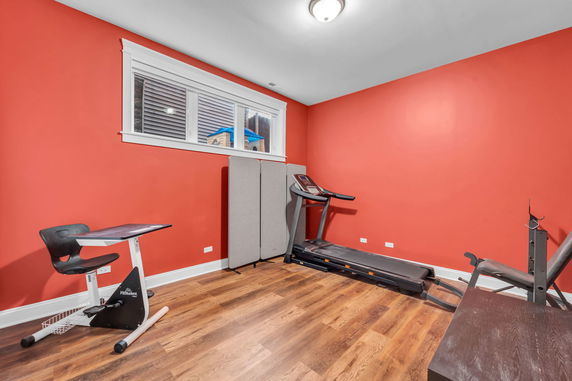 Indoor room with exercise equipment including a treadmill and a stationary bike-desk.