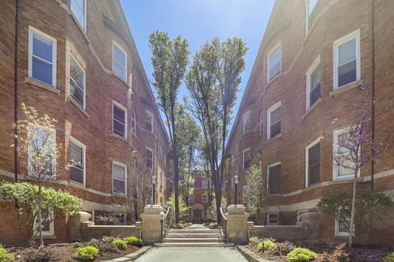 Front view of symmetrical brick apartment buildings with a central walkway.
