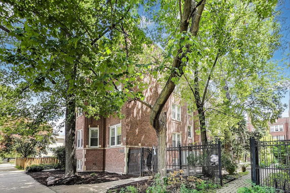 Front view of a brick building with multiple windows surrounded by trees.
