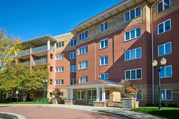 Front view of a multi-story brick building with balconies and large windows.