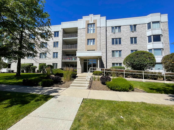 Front view of a four-story apartment building with balconies and a central entrance.