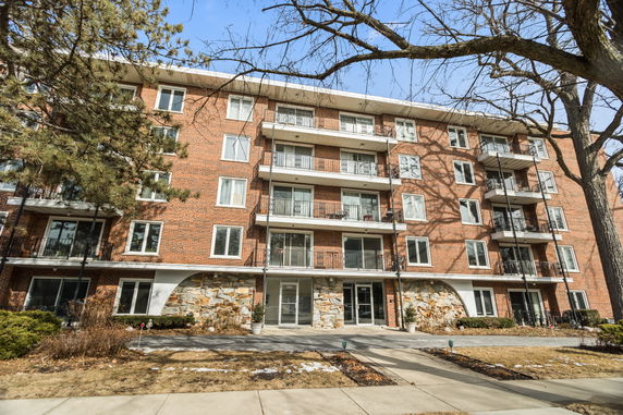 Front view of a multi-story brick apartment building with balconies.