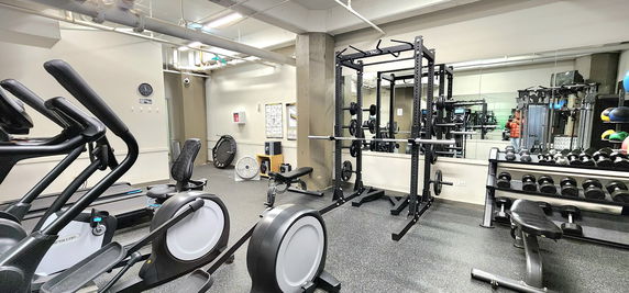 Indoor gym area with exercise equipment including treadmills, weights, and benches.