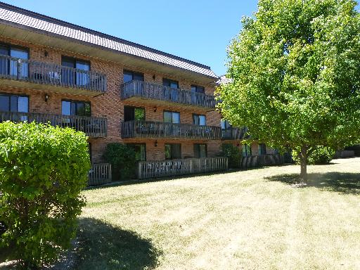 Front view of a multi-story brick apartment building with balconies.