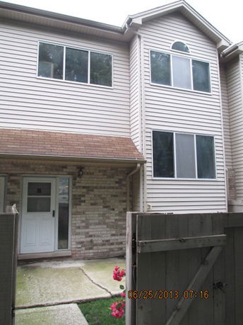 Front view of a two-story house with multiple windows and a fenced entry.
