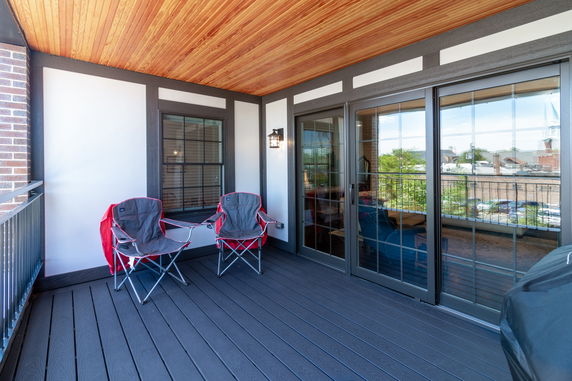 View from a balcony with chairs and glass doors overlooking a cityscape.