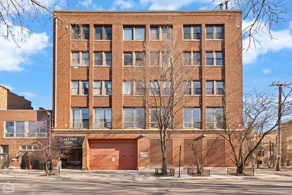 Front view of a multi-story brick building with large windows and a gallery entrance.