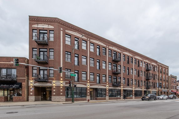 Front view of a multi-story brick building with balconies and storefronts.