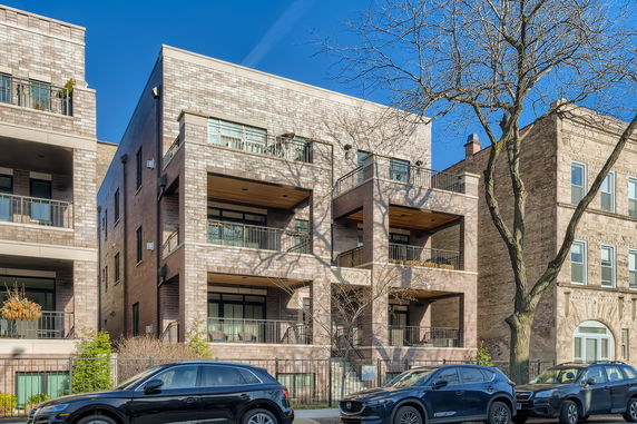 Front view of a multi-story building with balconies and brick facade.
