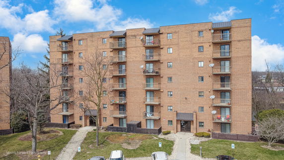 Front view of a multi-story brick apartment building with balconies.