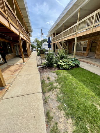 View between two residential buildings with upper wooden walkways.
