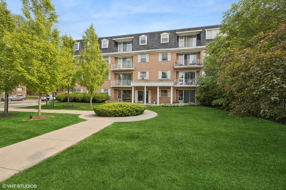 Front view of a multi-story brick apartment building with balconies.