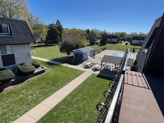 Panoramic view from a building showing surrounding areas with a lawn, pathway, and nearby structures.