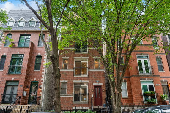 Front view of a multi-story brick house with large windows and a central entrance.