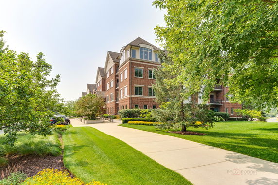 Front view of a multi-story brick apartment building with landscaped surroundings.