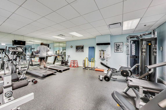 Interior view of a gym with exercise equipment including treadmills, ellipticals, and weight machines.