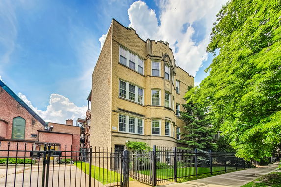 Front view of a multi-story brick building with multiple windows and a gated entrance.