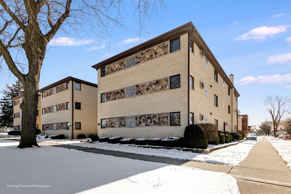 Front view of a multi-story apartment building with a brick facade.