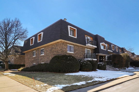 Front view of a two-story brick apartment building with dark roofing.