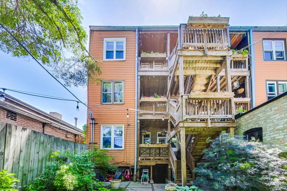 Rear view of a multi-story building with wooden balconies and staircase.