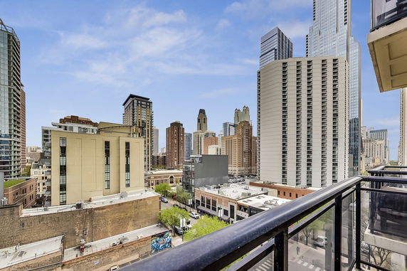 Panoramic view of a city skyline from a balcony, showing multiple high-rise buildings.
