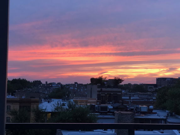Panoramic view of urban rooftops during a colorful sunset.