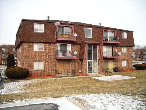Front view of a multi-story apartment building with balconies and brick exterior.