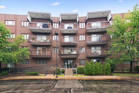 Front view of a multi-story brick apartment building with balconies.