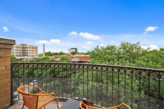 Balcony view showing buildings and trees in the surrounding area.