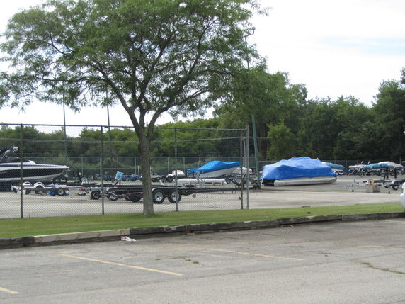 Outdoor parking area with boats covered in tarps.