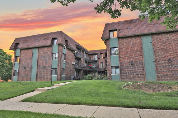 Front view of a multi-story brick apartment building with balconies.