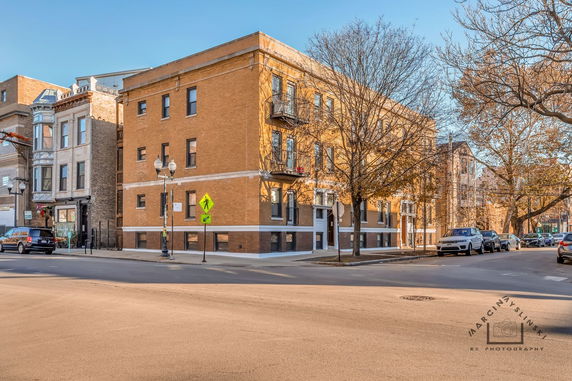 Front view of a three-story brick building on a city street corner.